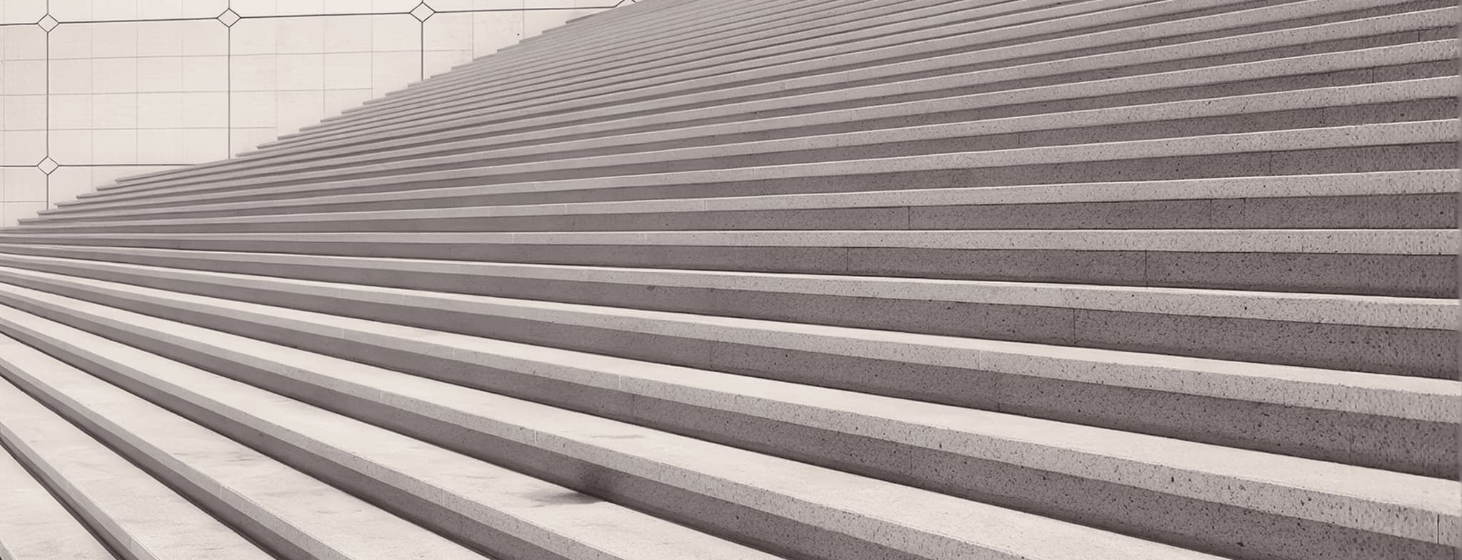 Modern concrete stadium steps with long parallel tiers and geometric tiled wall background