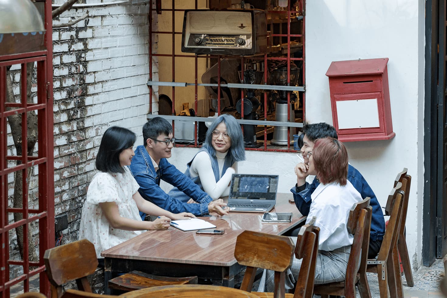 Group of friends using laptops in a cozy café table setting, casual teamwork and studying