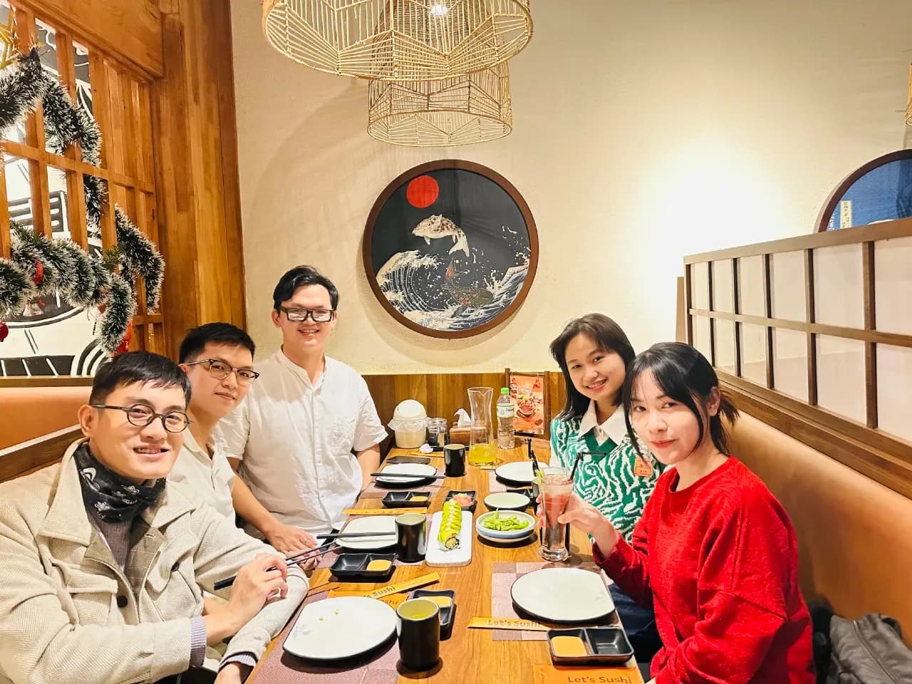 Group dinner at restaurant table with friends smiling, Asian cuisine setting, cozy indoor dining ambience