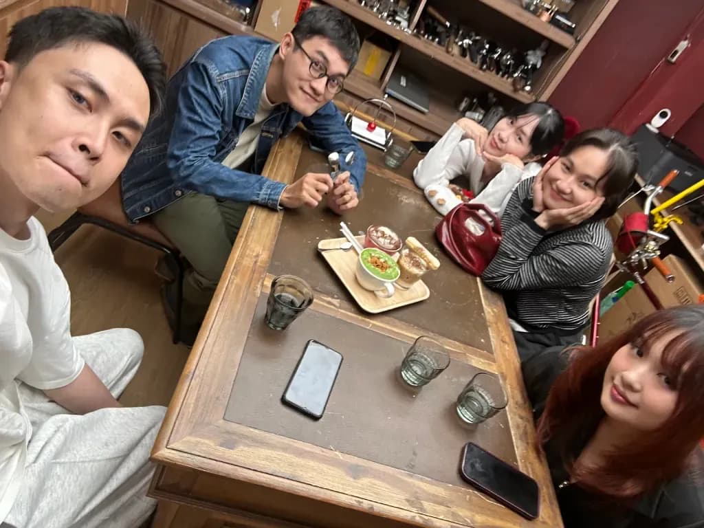Friends playing board game at a bar with drinks and snacks on table, casual hangout atmosphere