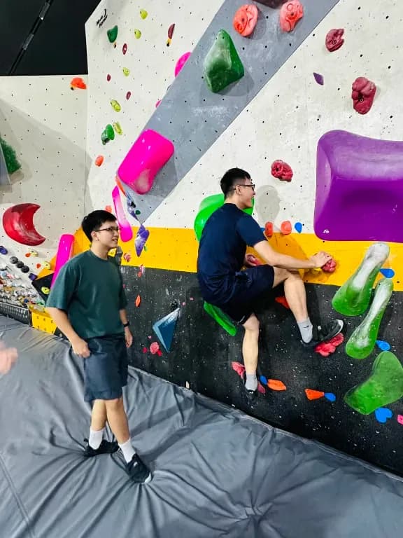 Indoor rock climbing gym wall with colorful holds, kids training on bouldering at an adventure center