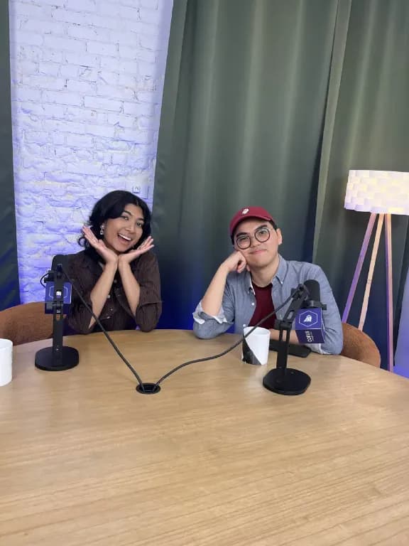 Podcast studio hosts smiling with microphones, recording episode with headphones and streaming setup