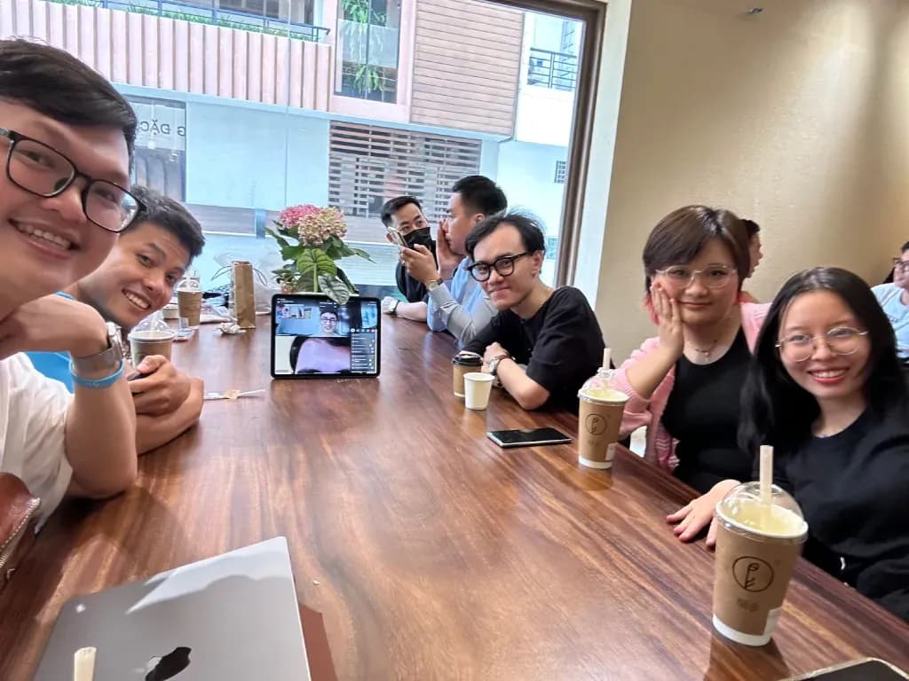 Group of friends at a cafe table, smiling and posing with iced coffee and drinks