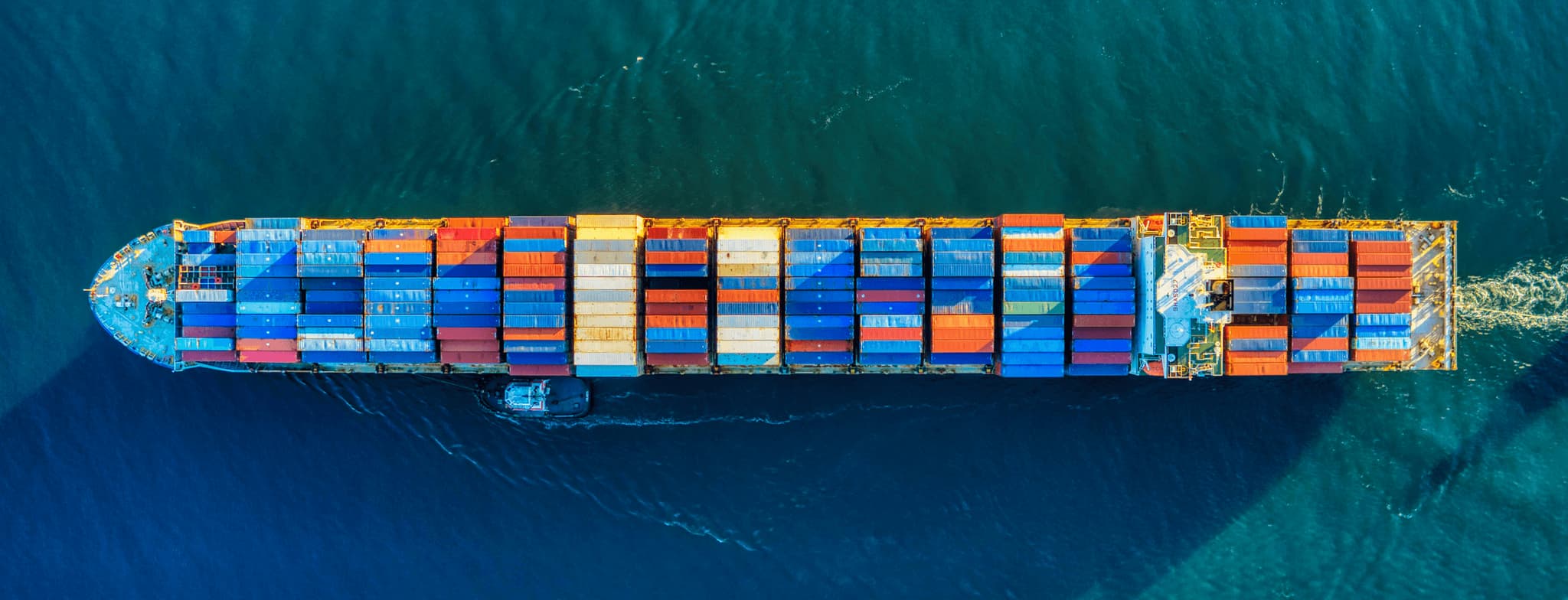 Aerial view of a container ship carrying colorful cargo containers through deep blue ocean water
